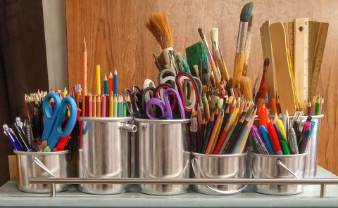 There is a collection of art supplies organized in tin containers